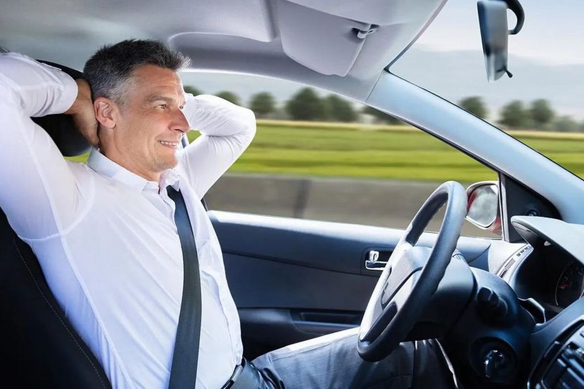  Um homem com relaxa enquanto usa o sistema de direção autônoma de um veículo Tesla ilustra nosso artigo sobre: Como receber o seguro em caso de perda total de carro financiado. (foto: StockPhotos)
