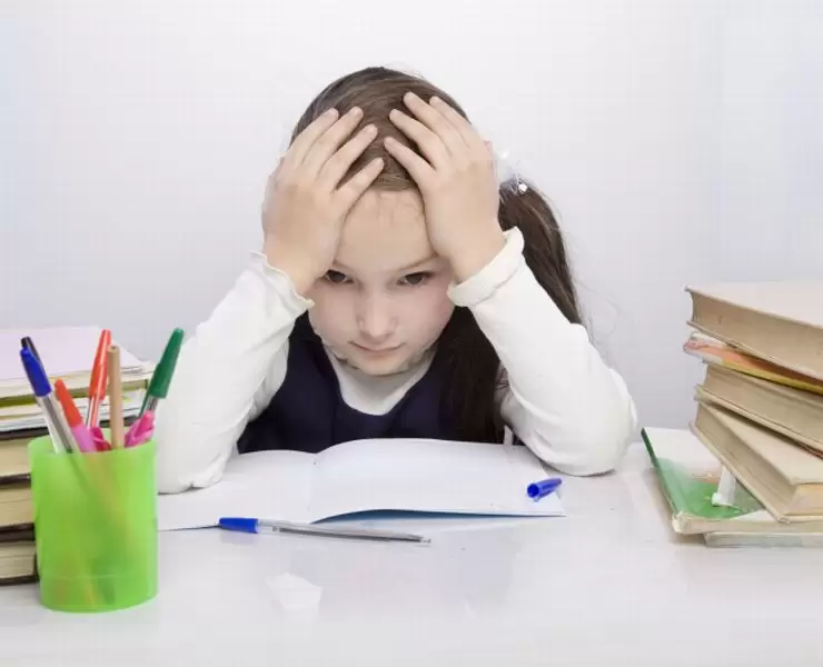 Uma criança demonstrando preocupação enquanto tenta fazer o dever de casa, apenas um aspécto do stress na vida da criança.