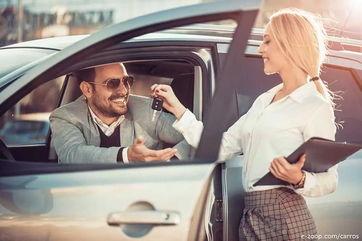 Cliente recebendo as chaves de seu carro novo de uma vendedora ilustra o nosso artigo sobre: Vai trocar de carro.