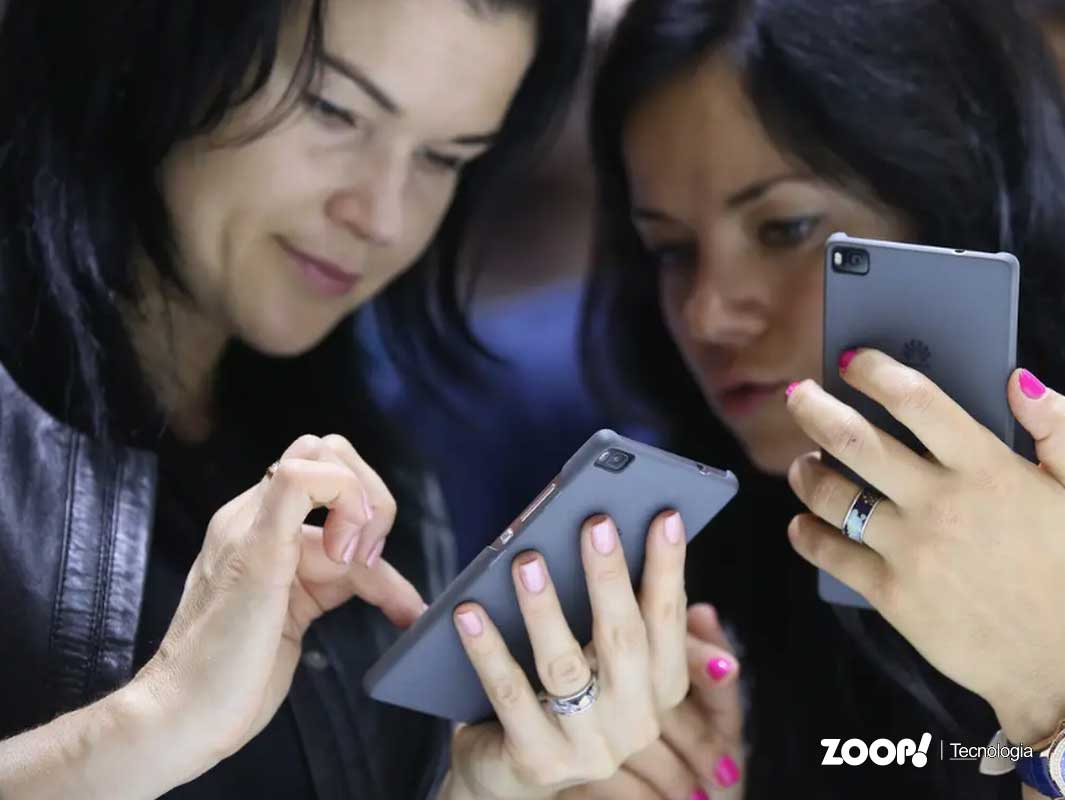 Duas mulheres verificando o número IMEI do celular.