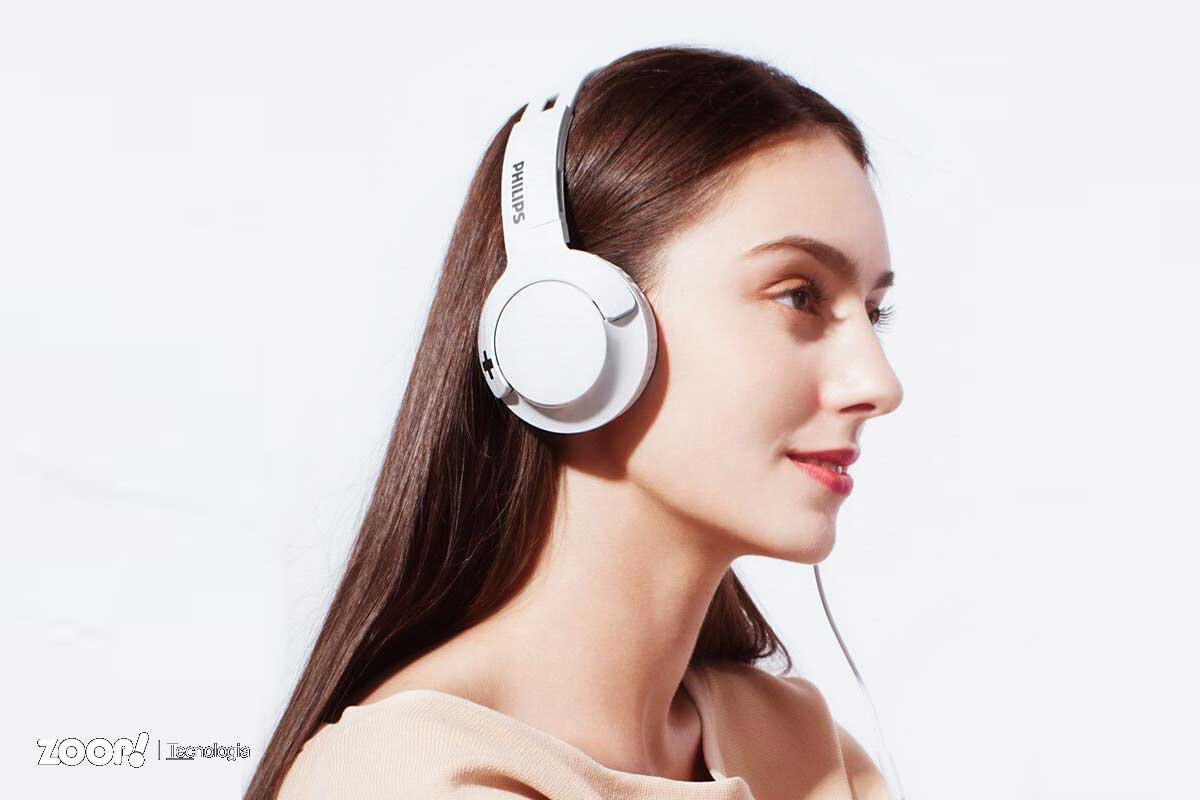 Mulher usando fone de ouvido com fio profissional marca Philips.