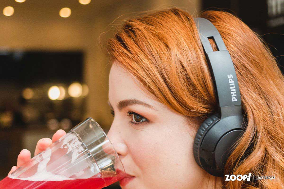 Mulher ruiva usando fone de ouvido com fio profissional marca Philips.