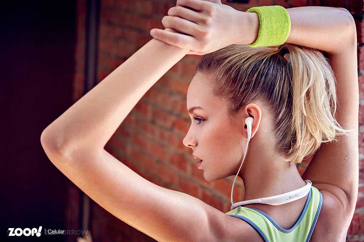 Mulher jovem usando fone de ouvido Bluetooth enquanto se exercita ilustra nosso artigo sobre: Como comprar fone ouvido bluetooth. 