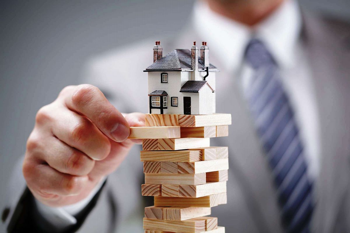 Um investidor de imóveis montando uma pilha de blocos ilustra nosso artigo sobre: Investir em Imóveis.