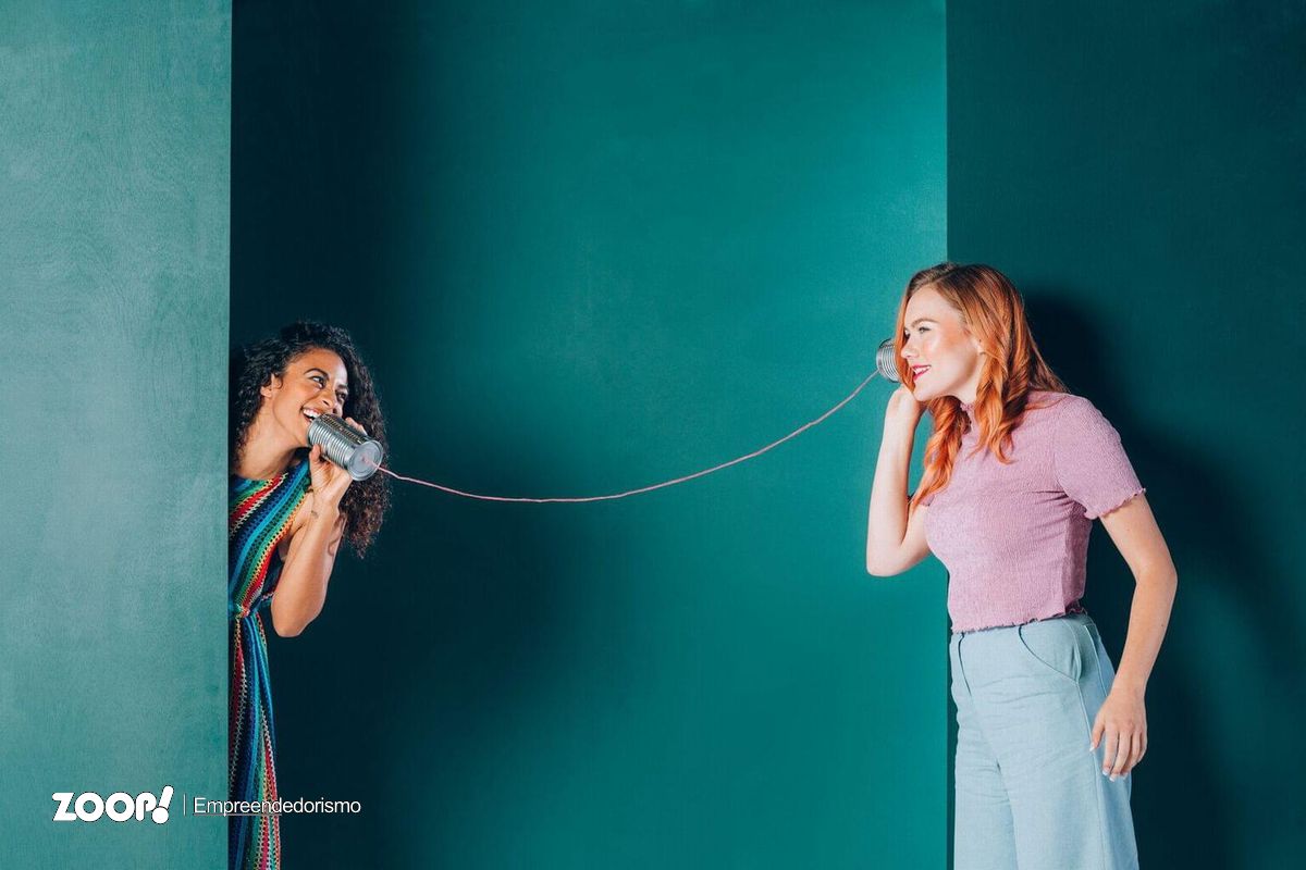 Duas mulheres falando num telefone de latainhas ilustra nosso artigo sobre: Dicas para a comunicação interna nas empresas. 