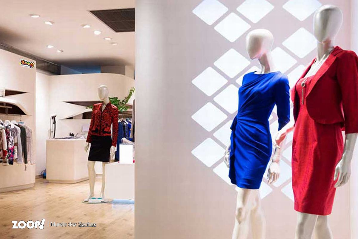 Dois manequins vestidos com vestidos azule e outro vermelho, na entrada de uma loja.