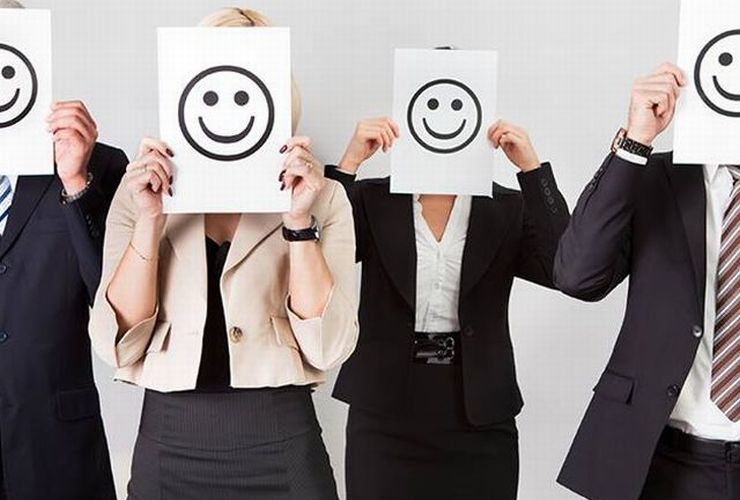 Pessoas seguram cartazes com desenho de emoji feliz em frente ao rosto ilustram nosso artigo sobre: Quer encontrar clientes nas redes sociais?