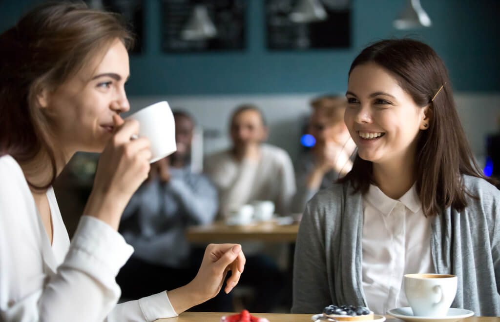 Duas mulheres conversando numa cafeteria ilustra nosso artigo sobre: Para construir relações mais significativas em mídias sociais, é preciso humanizar sua marca. (imagem: iStock)