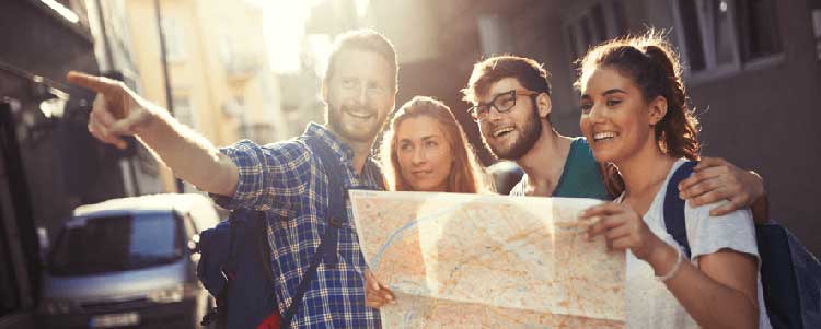 Quatro jovens turístas, dois homens e duas mulhers, segurando um mapa de papel.