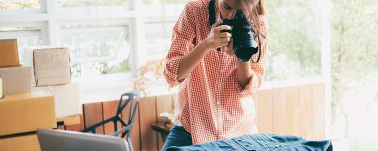 Uma mulher jovem usando uma máquina fotográfica profissional para fotografar uma peça de roupa.