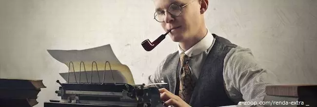 Um detador, jovem usando óculos e segurando um cachimbo entre os dentes escreve à máquina de escrever.