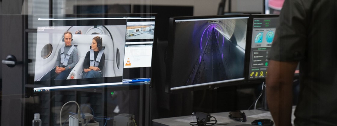 Uma pessoa observa o interior do Uma foto do interior do Hyperloop através de telas de computador. 