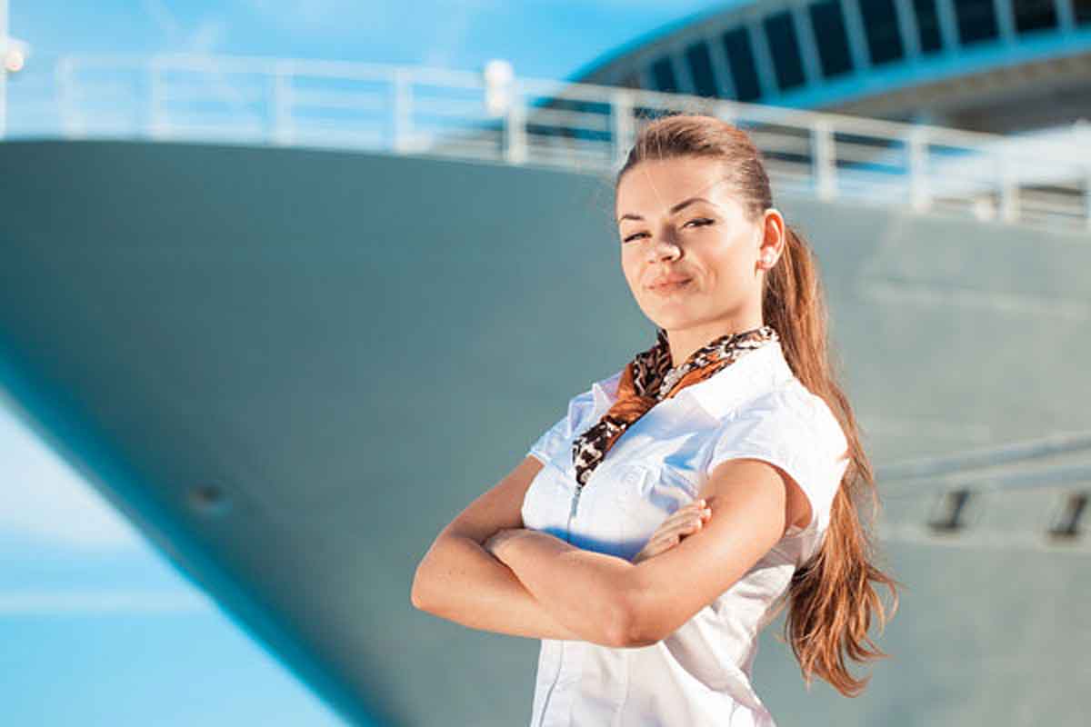 Mulher loira jovem posando para foto em frente a um navio de cruzeiro se preparando para sua viagem solo.
