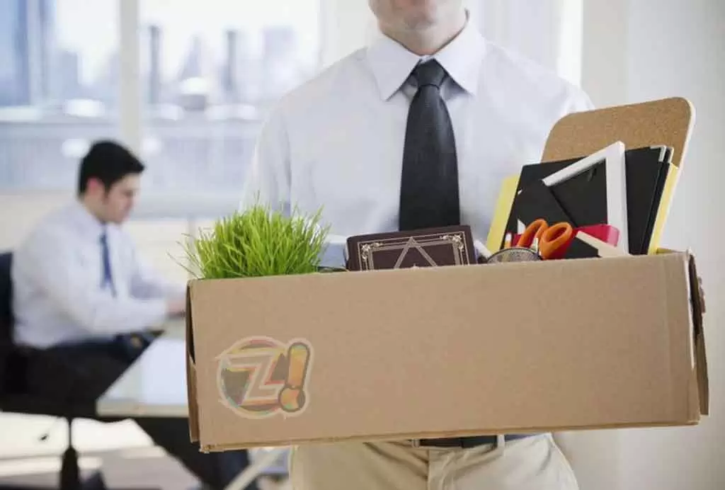 Um homem carrega uma caixa de papelão com objetos pessoas após ter sido demitido ilustra nosso artigo sobre: O que NÃO fazer se você quer manter seu emprego.