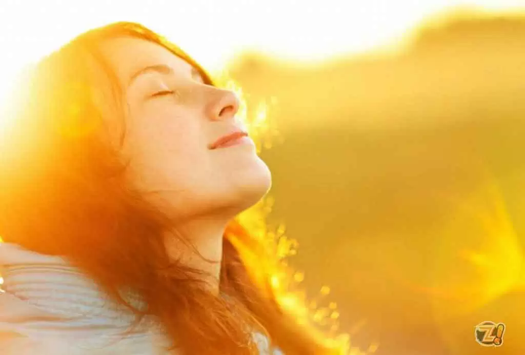 Uma mulher com os olhos fechados tomando o sol da manhã  ilustra nosso artigo sobre: Sinais de que está na hora de mudar de emprego.