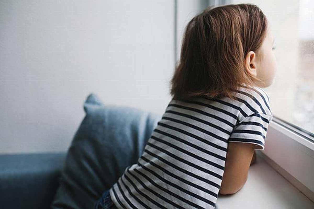 Uma criança olhando pela vidraça da janela ilustra nosso artigo sobre: Dez maneiras de ajudar a criança a lidar com a ansiedade