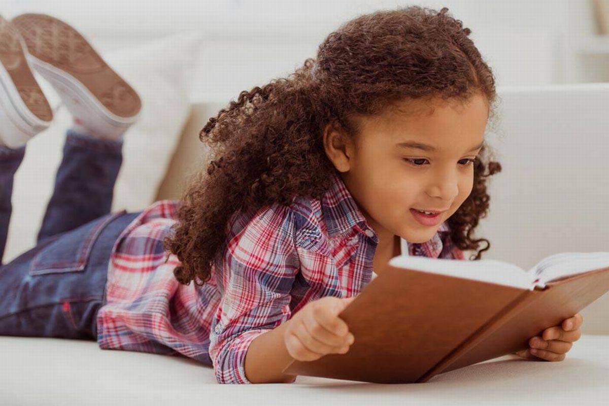 Uma criança lendo ilustra o nosso artigo sobre: Entenda a importância da leitura infantil