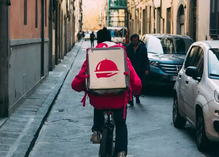 Um entregador de aplicativo numa bicicleta ilustra nosso artigo sobre: Como gerenciar restaurantes delivery com sucesso: 5 dicas