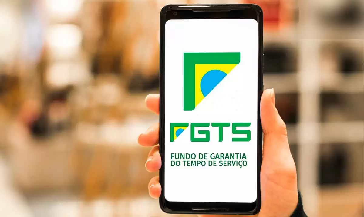 Uma pessoa usando app do FGTS na frente de um notbook com site da Caixa aberto. Uma pessoa usando app do FGTS na frente de um notbook com site da Caixa aberto.
