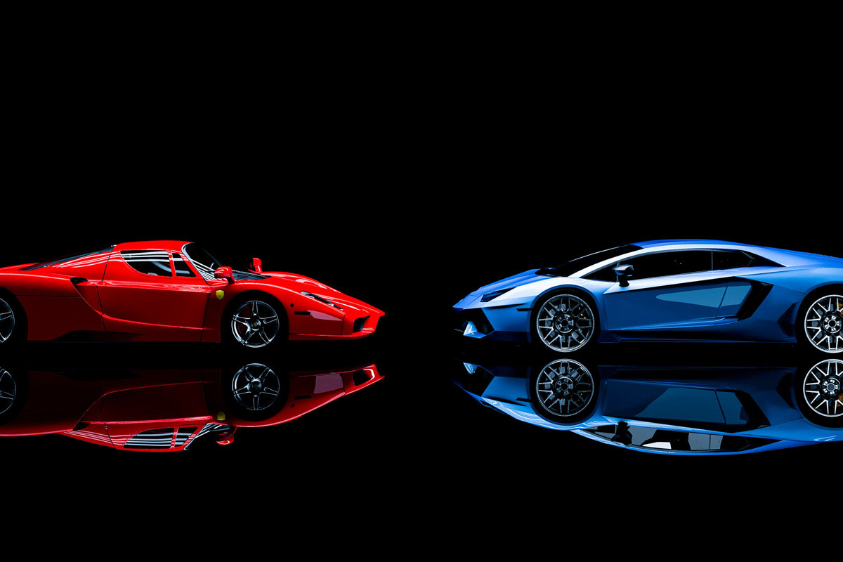 Ferrari ou Lamborghini? O que cada uma significa? Uma Ferrari vermelha de frente para uma Lamborghini azul ilustrando nosso artigo sobre: Ferrari ou Lamborghini