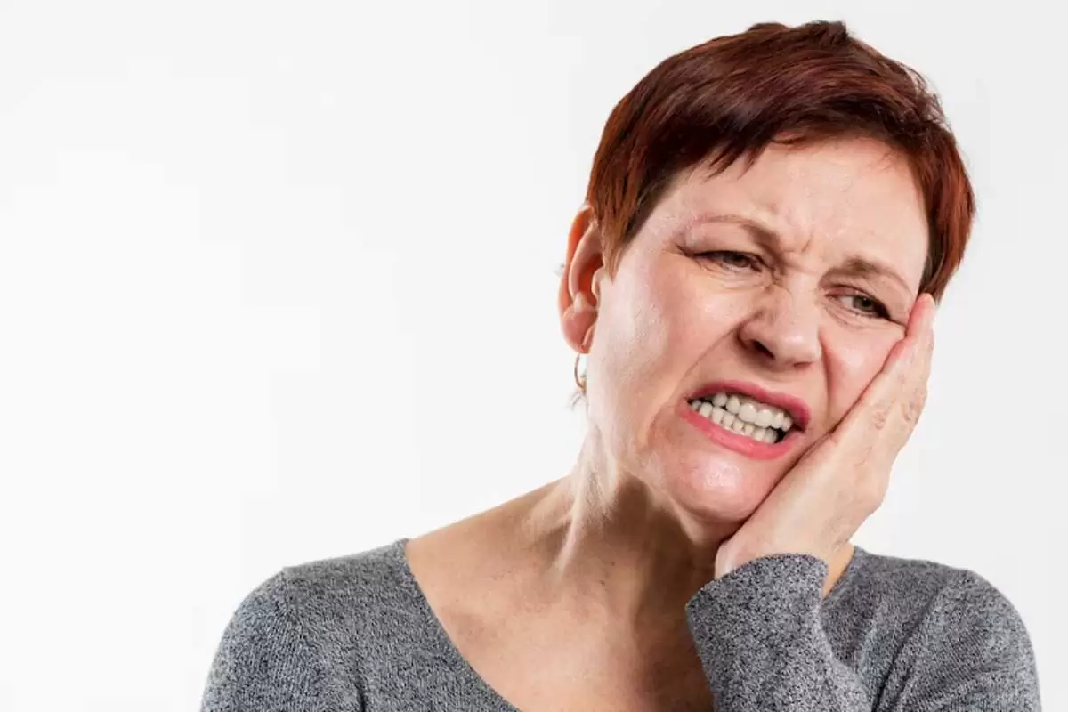 Mulher demonstrando que está com dor de dente ilustra nosso artigo sobre: Sonhar com dente caindo - Créditos da imagem: Freepick.com.