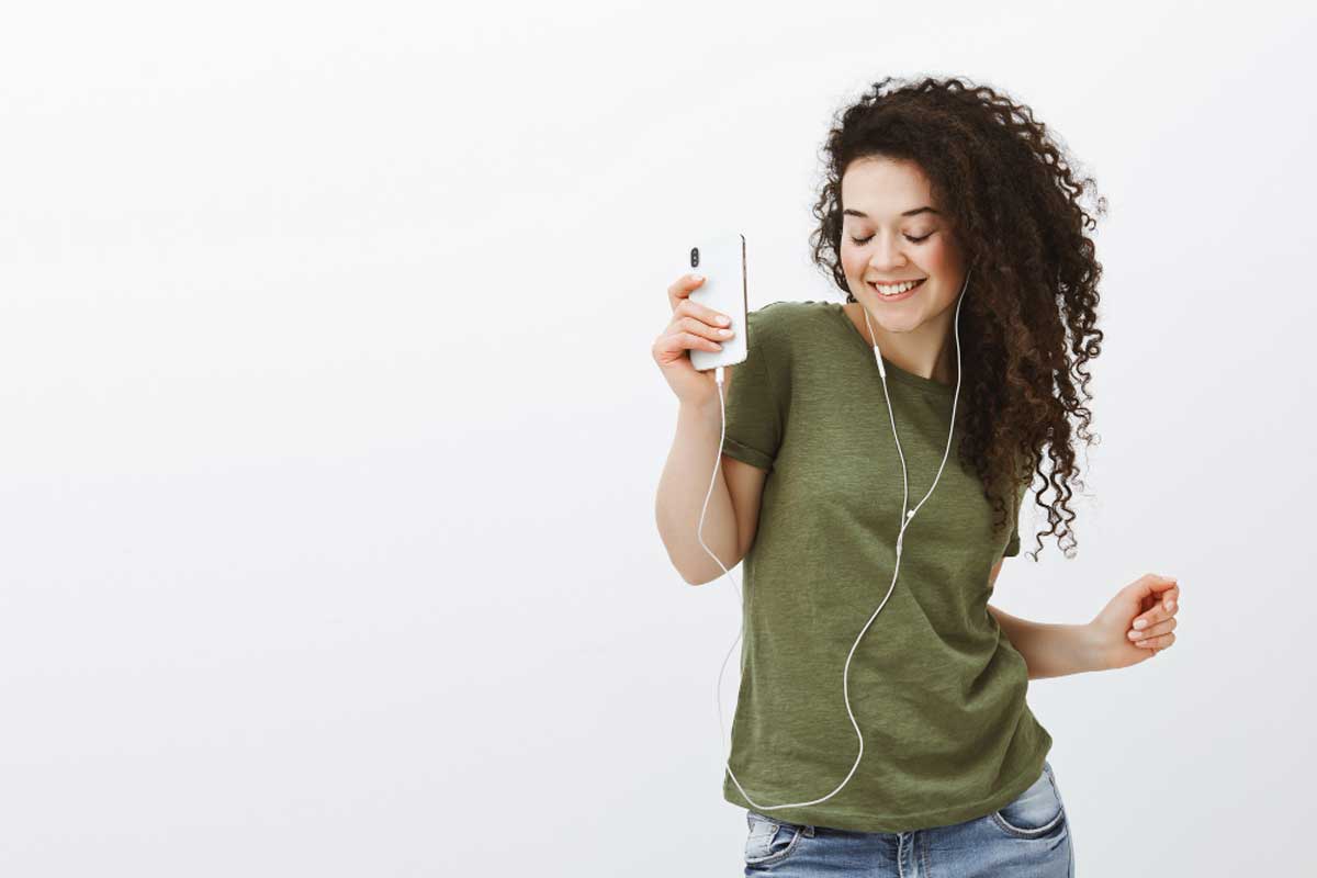 Uma mulher dança ao ouvir música no celular ilustra nosso artigo sobre: Como adicionar toques personalizados no Android. Créditos da Image: Freepik.com Uma mulher dança ao ouvir música no celular ilustra nosso artigo sobre: Como adicionar toques personalizados no Android. Créditos da Image: Freepik.com