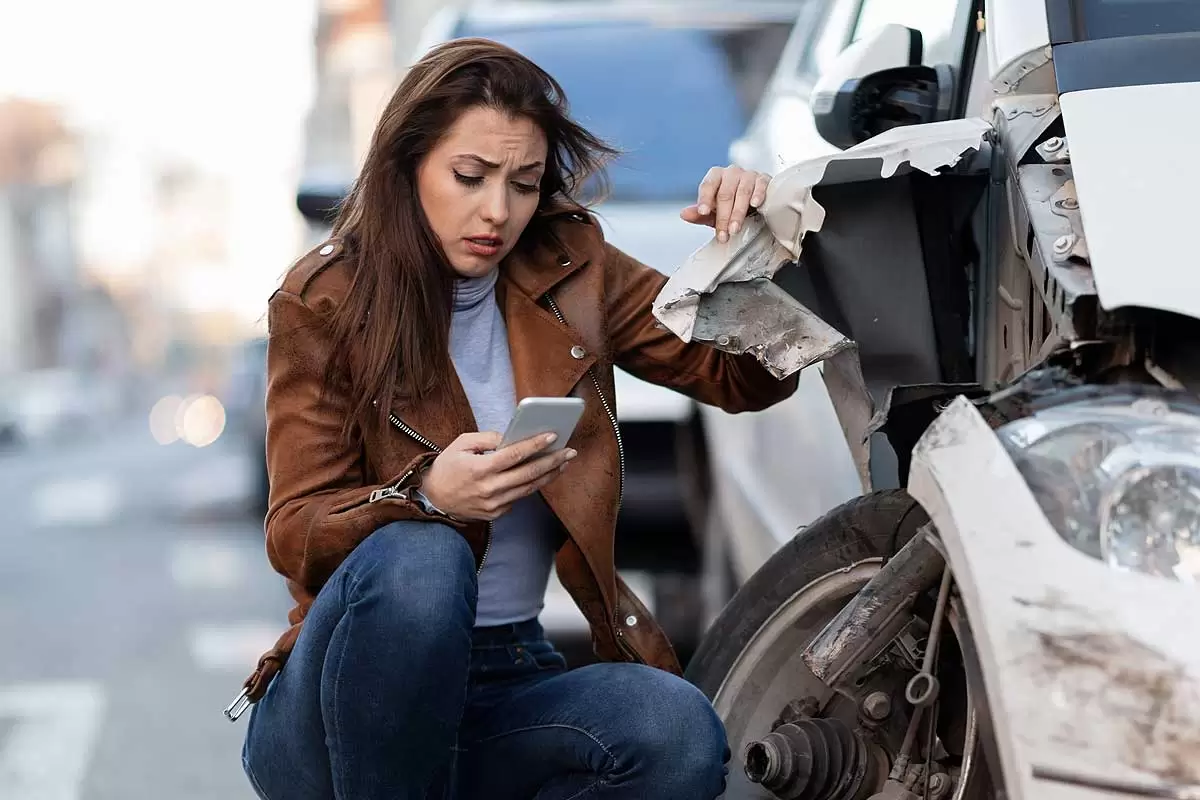 Uma mulher usando celular após um acidente de carro ilustra nosso artigo sobre sonhar com acidente de carro. Créditos da imagem: freepik.com Uma mulher usando celular após um acidente de carro ilustra nosso artigo sobre sonhar com acidente de carro. Créditos da imagem: freepik.com