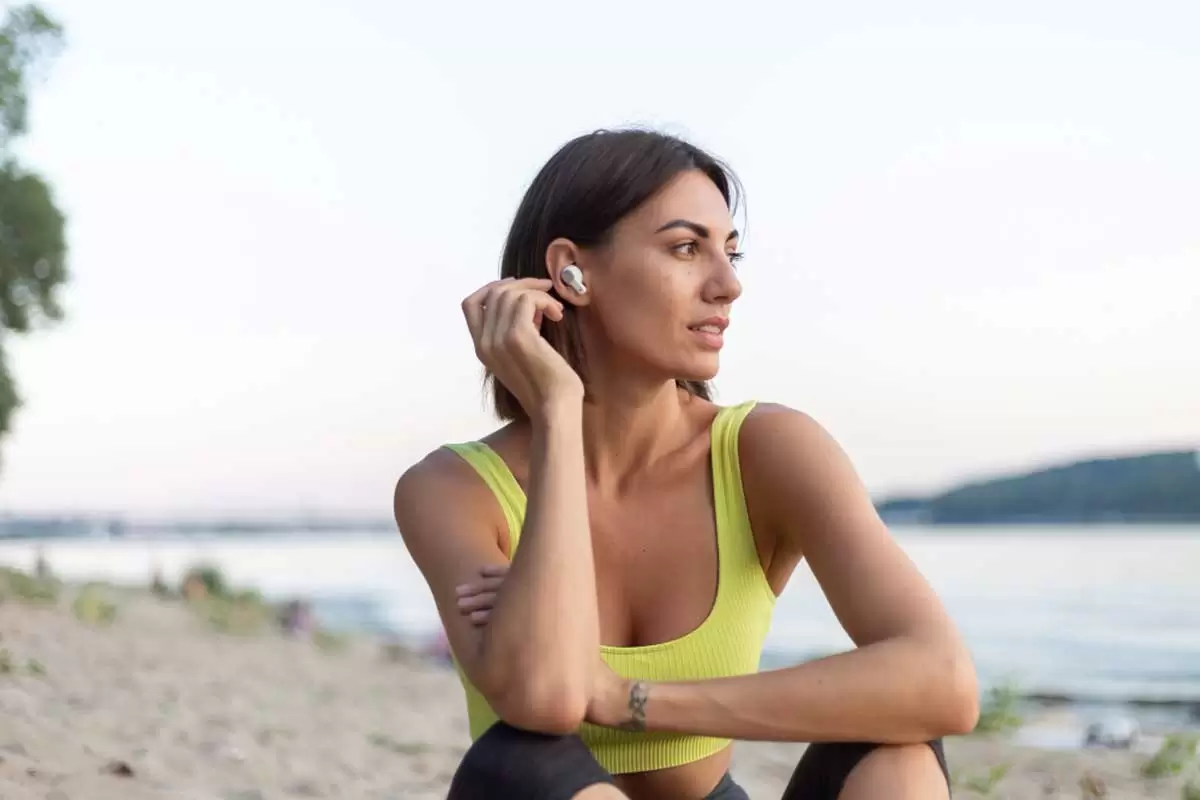 Uma mulher usando fones de ouvido bluetooth ilustra nosso artigo sobre AirPods e Radiação. Créditos da imagem: freepik.com