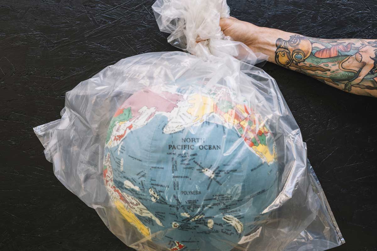 Microplásticos no corpo humano: por que você deveria se preocupar? Uma pessoa segurando um saco de plástico com o globo terrestre dentro ilustra nosso artigo sobre microplásticos. Créditos da imagem: Freepik.com