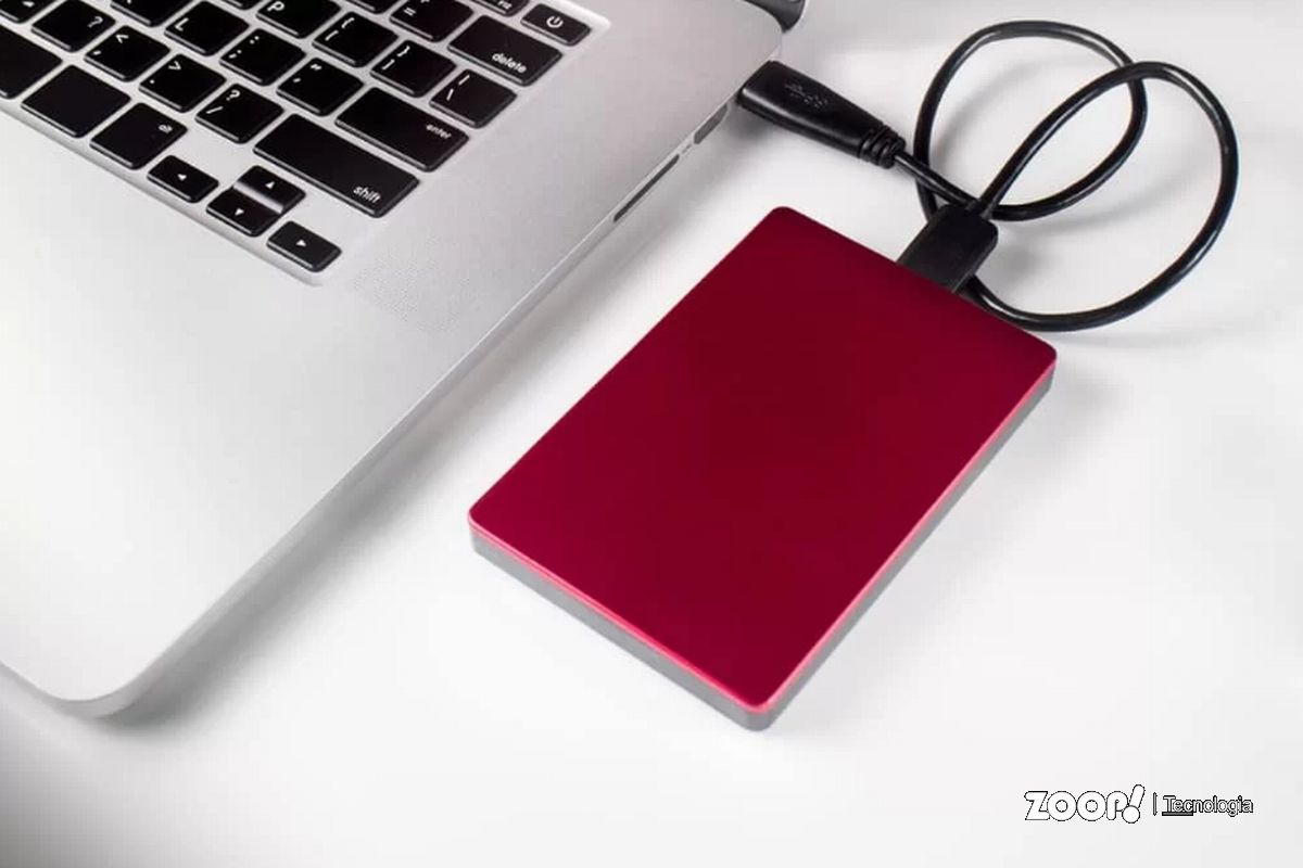 Um HD externo vermelho conectado a um Macbook ilustrando nosso artigo sobre HD externo e recuperação de arquivos. 