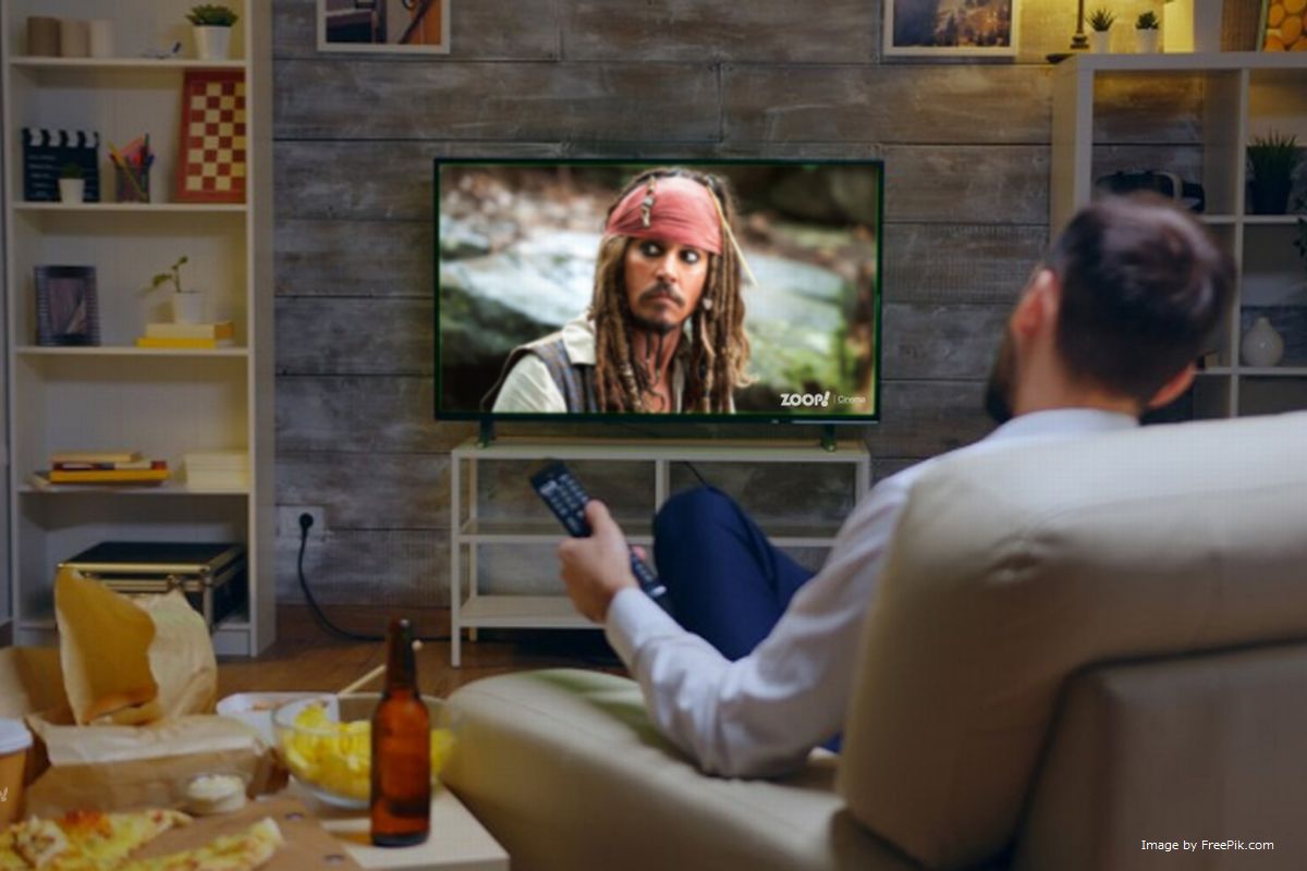 Um homem assistindo TV box pirata ilustra nosso artigo sobre: Como saber se minha TV Box é legal? Identifique aparelhos piratas.