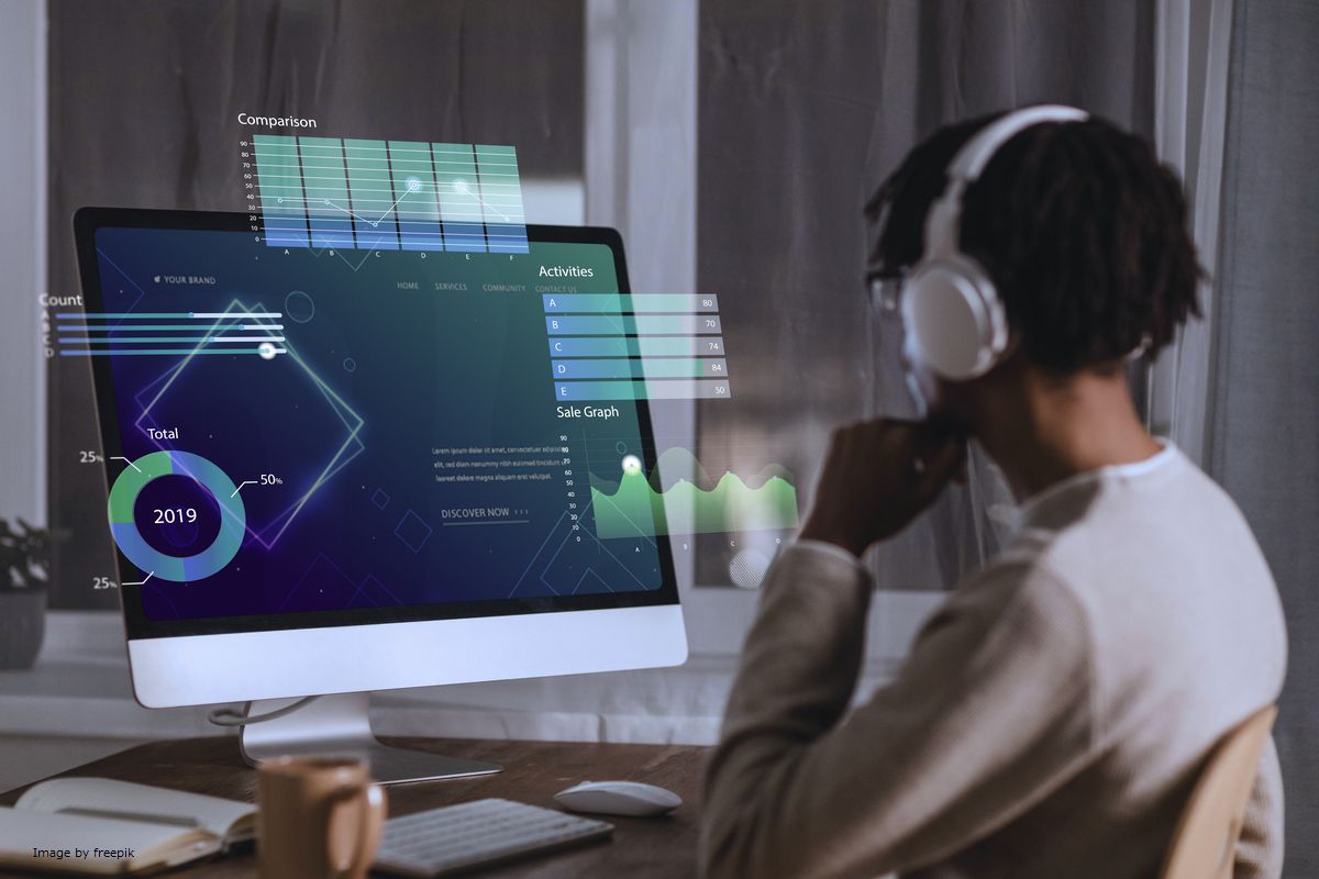 Um homem usando fones de ouvido em frente ao computador ilustra nosso artigo sobre: O que é tecnologia digital e como poderia ajudar seus negócios?