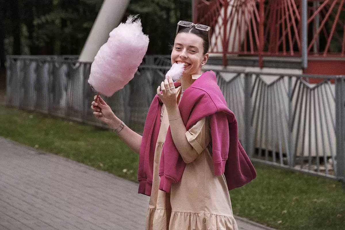 Uma mulher sorridente come algodâo doce na Disney. Créditos da imagem: freepik.com