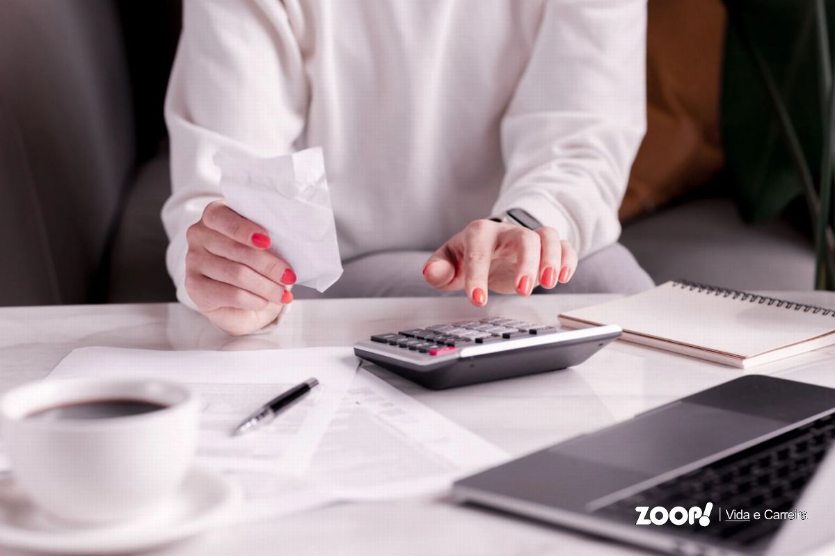 Uma mulher usando uma calculadora ilustra nosso artigo sobre: Redução de custos: dicas de como aplicar na empresa.