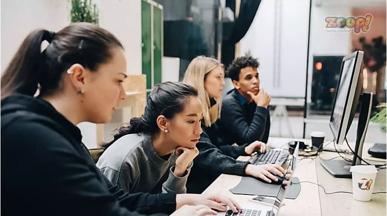 Jovens em  frente ao computador acessando a rede social que paga para postar conteúdo.